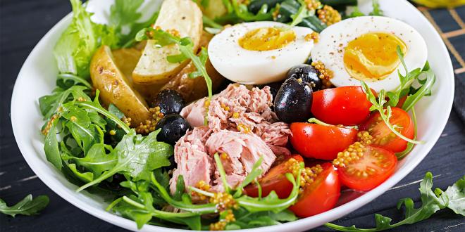 a salad of greens with eggs, cherry tomatoes, potatoes, and ham